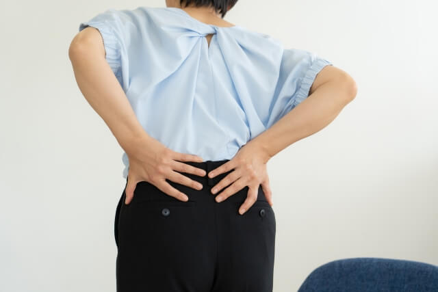 腰を両手で押さえる女性