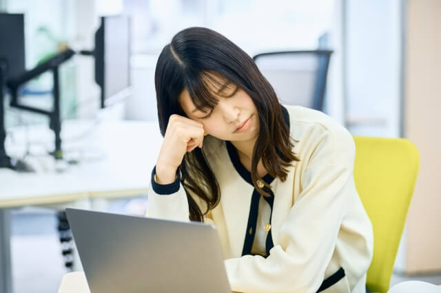 パソコンの前で頬杖を付く女性